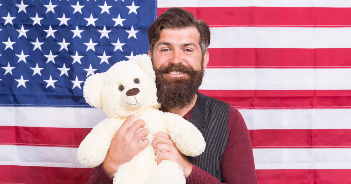 Mann vor US-Flagge mit Teddybär